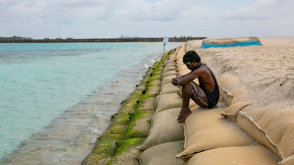 Man sitting on sand bags on ocean edge