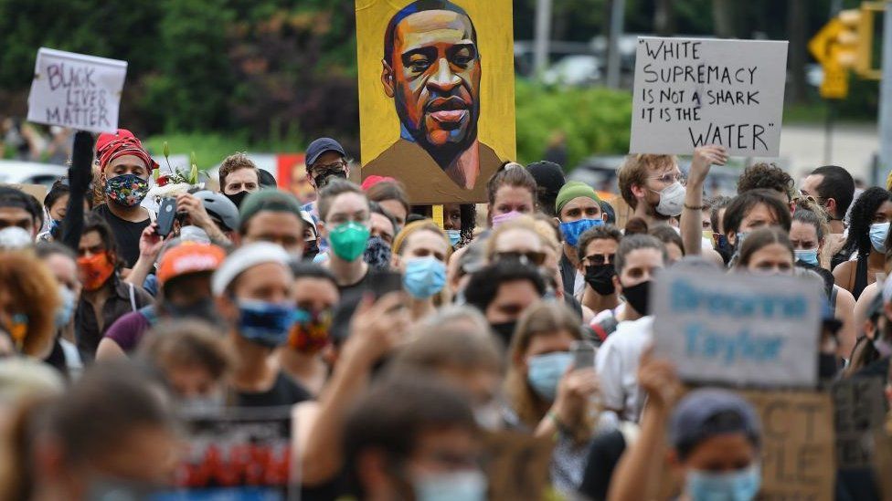 Protesters in June hold up a poster of George Floyd, who was killed by police in May