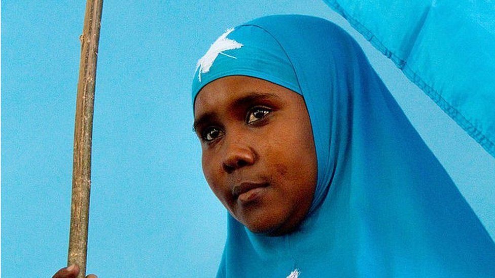 Сомалийская женщина держит национальный флаг во время церемонии, посвященной первому году правления президента шейха Шарифа Шейха Ахема, в президентском дворце «Вилла Сомалиа» в Могадишо, 29 января 2010 г.