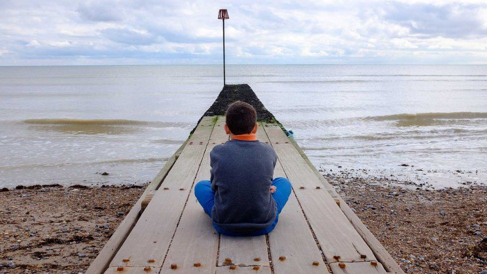 A boy sitting on a jetty