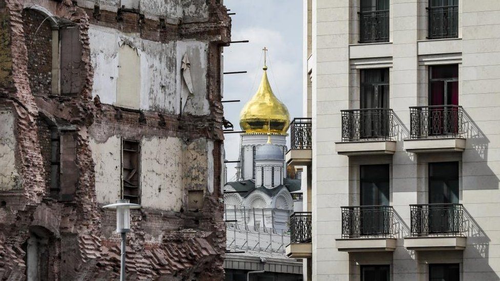 The Orthodox Church is seen between a new residential building and a partially destroyed old building in Moscow, Russia, 21 August 2023.