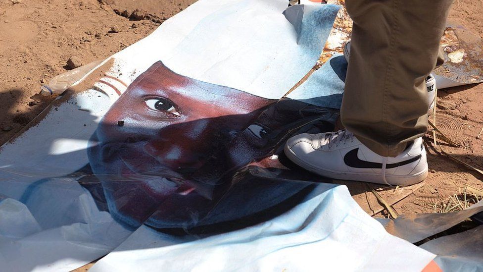 A supporter of the opposition foots a poster showing Jammeh's face on close-up