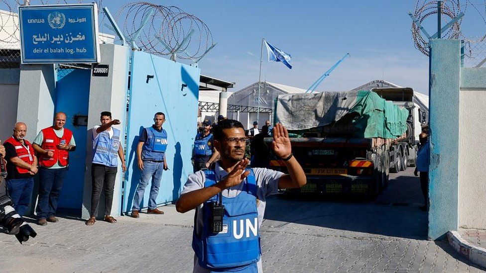 A UN worker assists aid trucks arriving into at a storage facility on 21 October