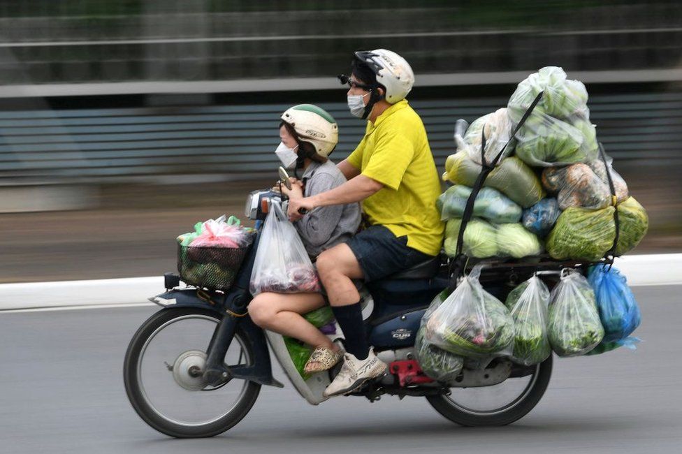 A man riding a heavily laden motorbike with a child