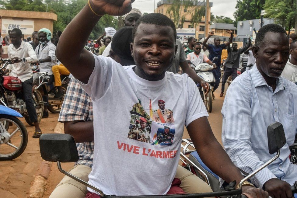 Man wearing shirt with the Niger, Mali, Guinea and Burkina Faso junta leaders on it.