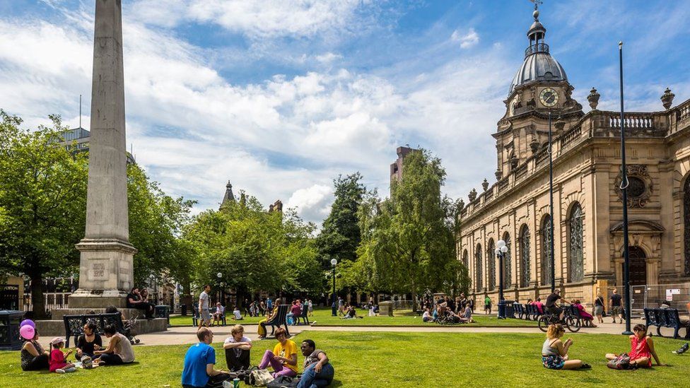 People sit on the grass in front of St Phillip's Cathedral in Birmingham