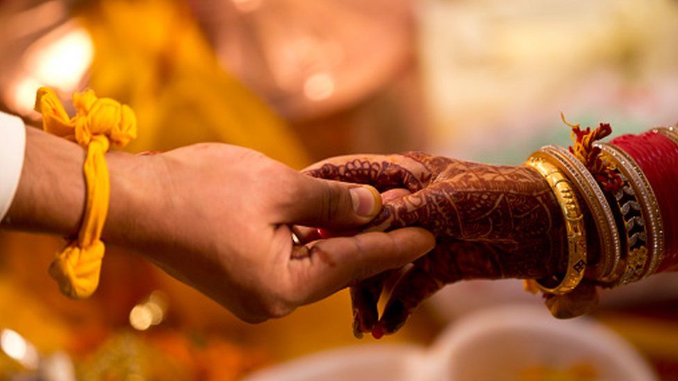 ndian bride and groom holding hands during wedding ceremony