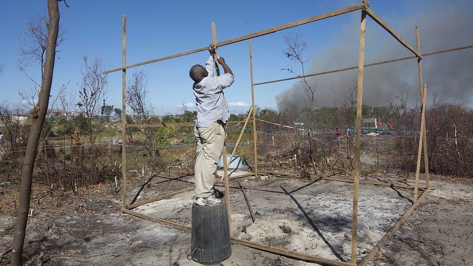A man builds a shack after he joined people from a neighbouring informal settlement in Khayelitsha, in occupying land allegedly belong to the South African national weapons manufacturer, DENEL on April 7, 2015.