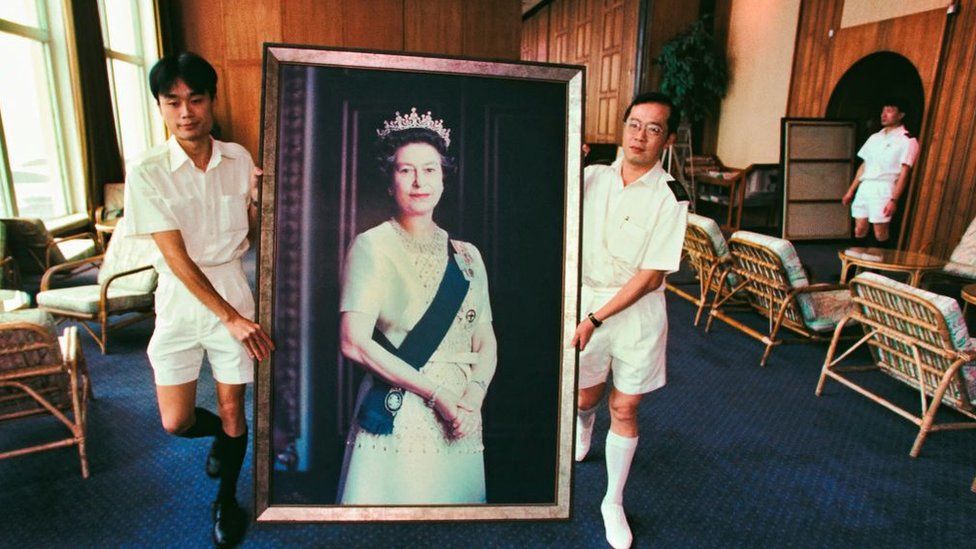 Два моряка Королевского флота в последний раз несут портрет британской королевы Елизаветы II, снятый со стены 16 июня 1997 года