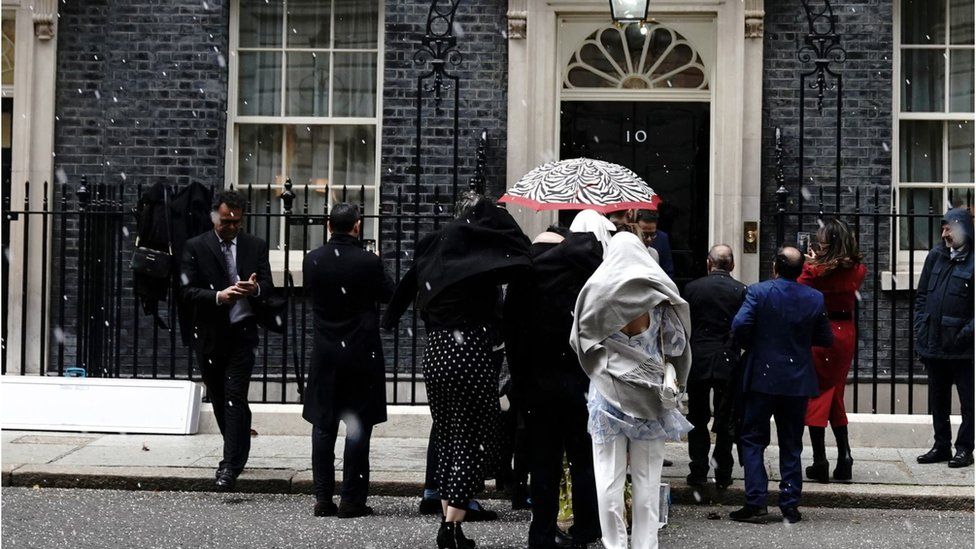 Members of the Muslim community queue as they wait to have their picture taken in front of 10 Downing Street's door, as they arrive for an Eid reception
