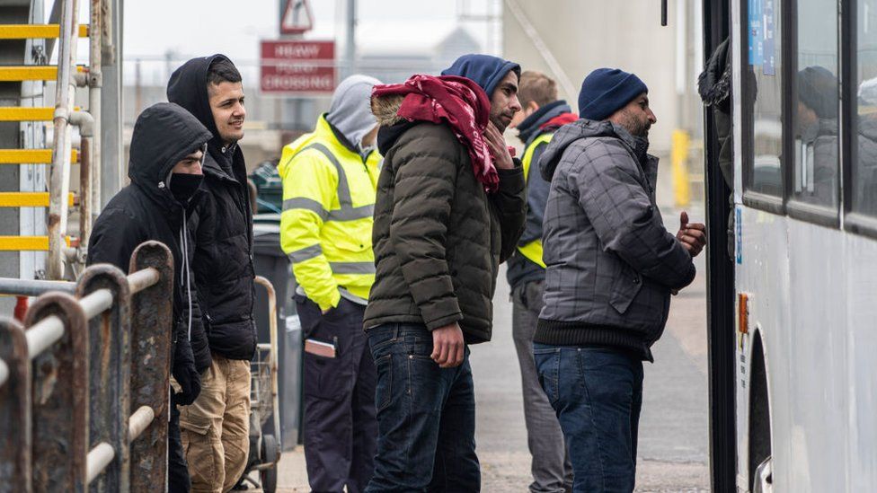 Migrants board a bus in Dover