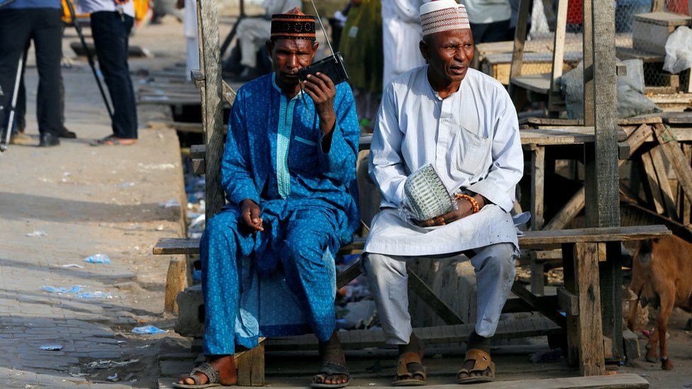 Two men listen to the radio as Nigerians await the results of the Presidential election, in Kano, Nigeria February 24, 2019.