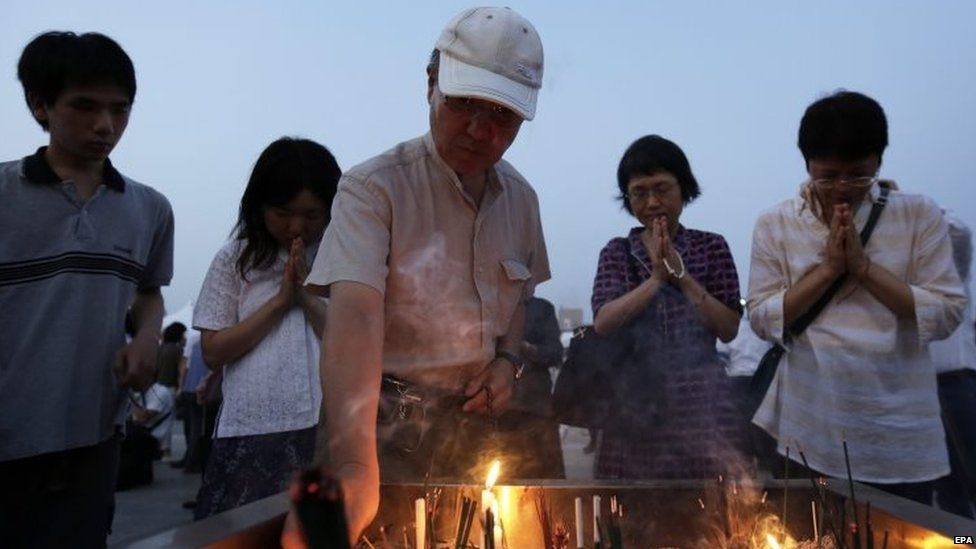 A man lights an incense stick while others offer prayers for victims of the atomic bombing during World War Two in Hiroshima (06 August 2015)