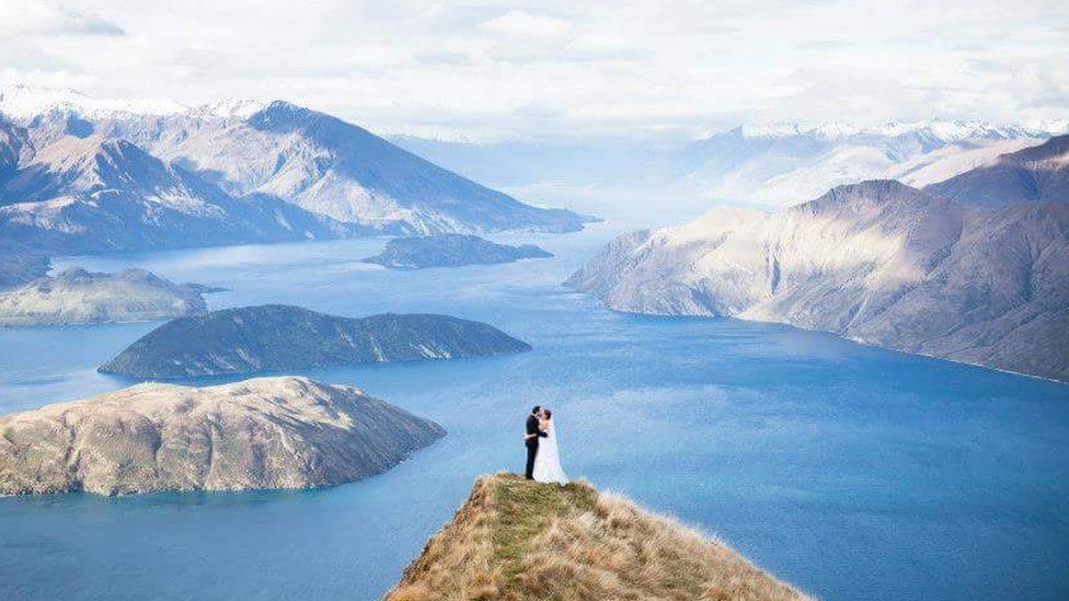 Aerial photograph of Kristy and Corey Rousseau in their wedding outfits on top of Roy's Peak in New Zealand
