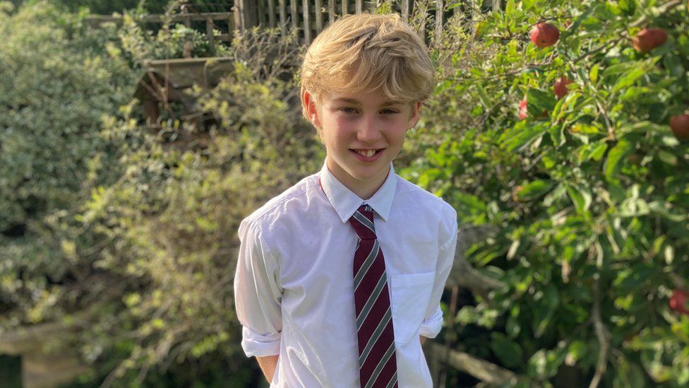 Maxi stood by an apple tree in his garden wearing his school tie and a white shirt
