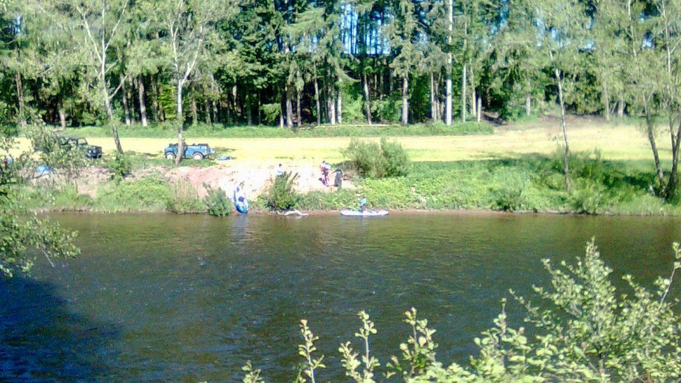 A group of off road vehicles on the banks of the river