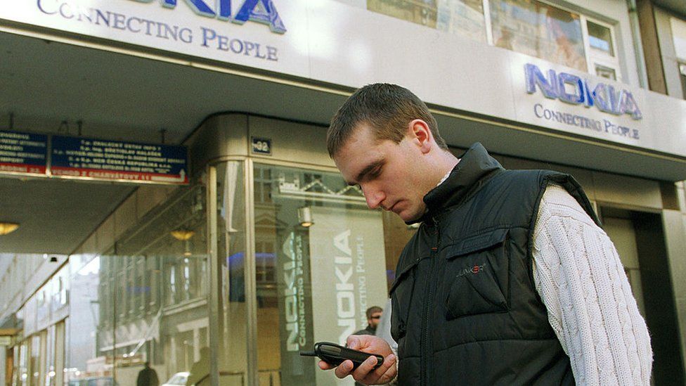 A man uses his mobile in front of a Nokia store in 2001