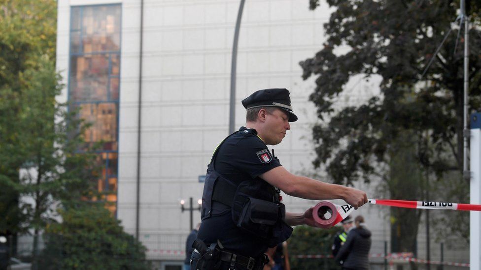 A police officer rolls out tape in front of the synagogue