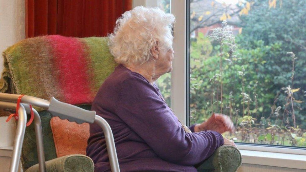 Elderly lady in chair near window