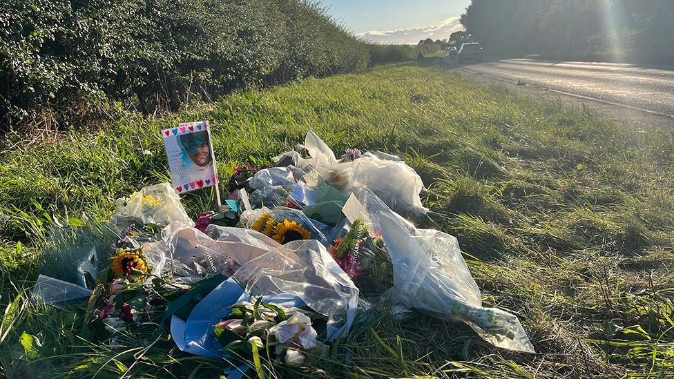 Bouquets of flowers lying on the grass next to the A53 