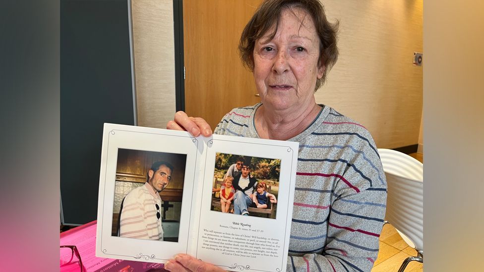 Jenny Fowler holding the funeral card of her husband