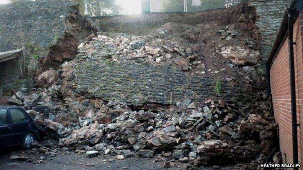 Collapsed section of wall as it originally fell in 2013, with large chunks of stone masonry strewn down a bank.