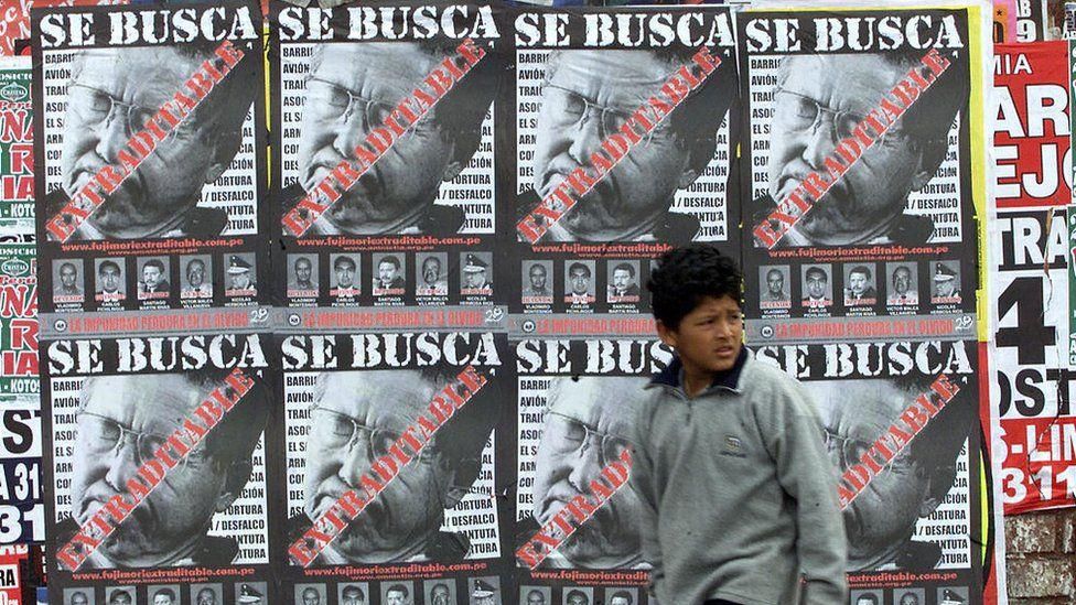 A boy passes "Wanted" posters in Lima calling for the extradition of former Peruvian President Alberto Fujimori 30 July, 2003