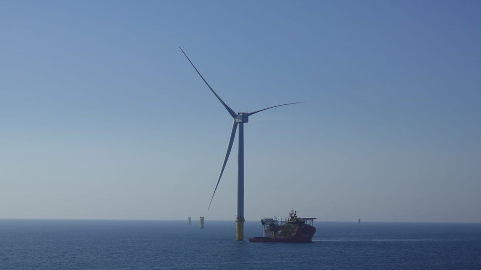 One of the wind turbines in the sea with a ship moored alongside it