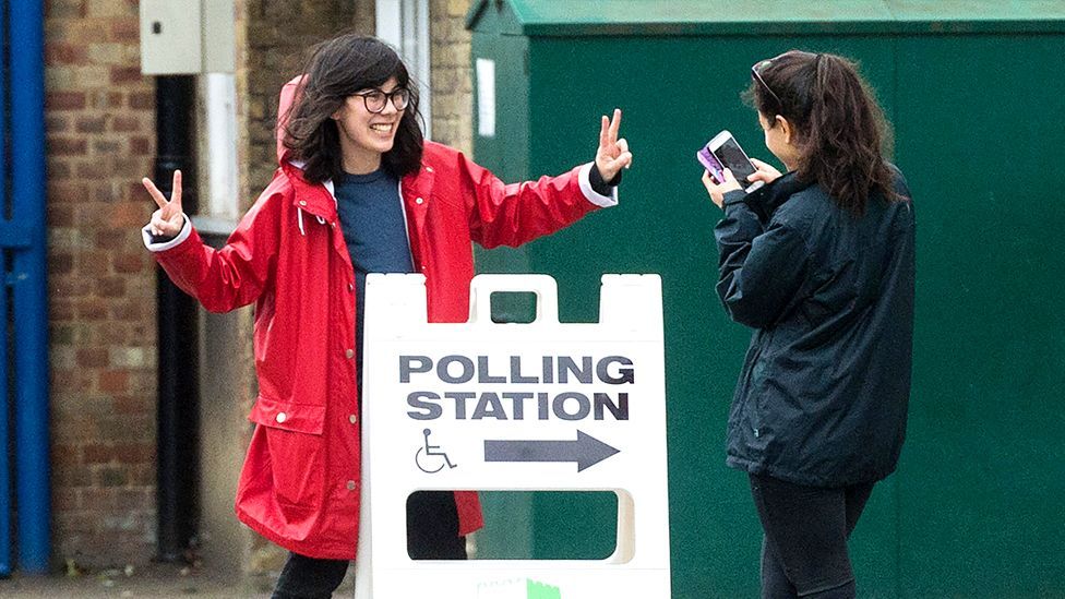Two young voters take a photo outside a polling station during the UK General Election in June 2017