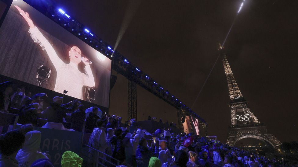 Celine Dion seen on a big screen next to the Eiffel Tower