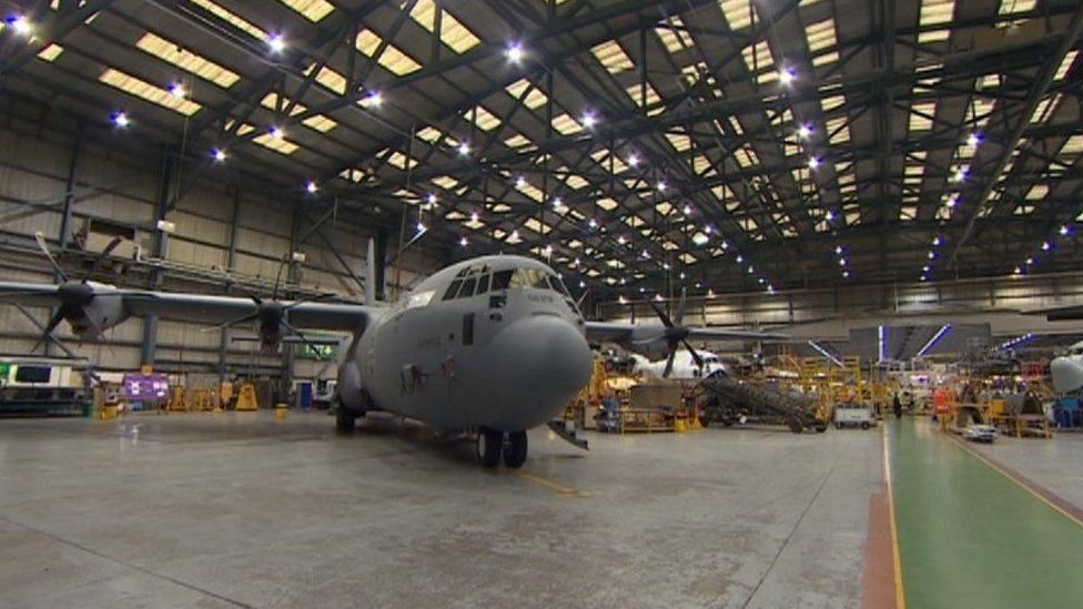 A large grey aeroplane in a hanger with others behind it