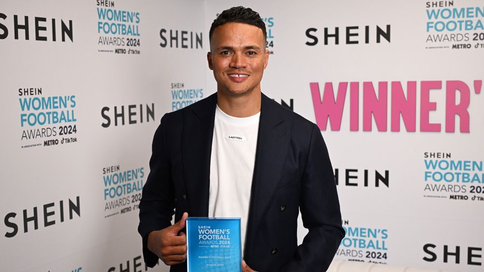 Jermaine Jenas smiling and holding up an award at the Women's Football Awards