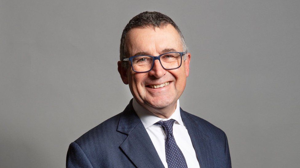 Sir Bernard Jenkin, who is wearing a suit, tie and glasses. He is smiling at the camera