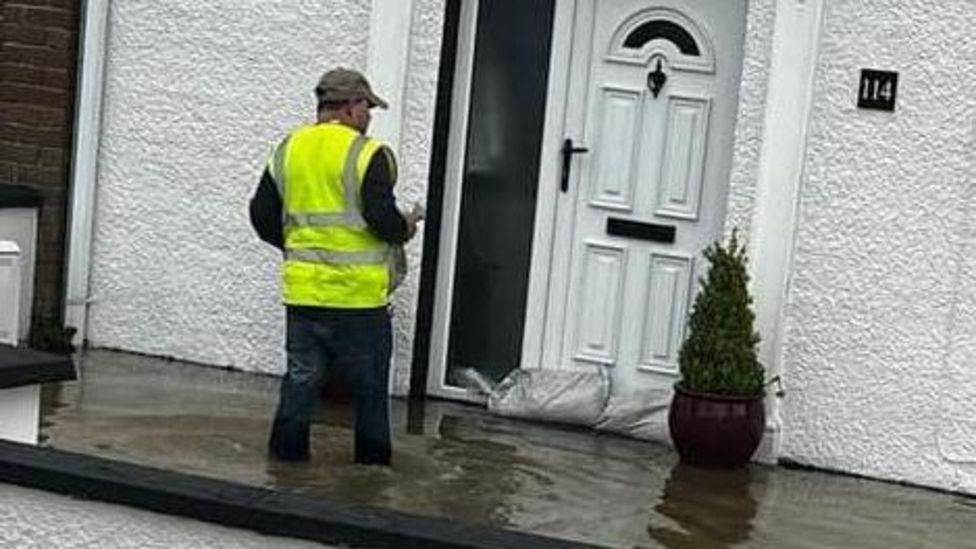 worker calling at door of flooded home in derry