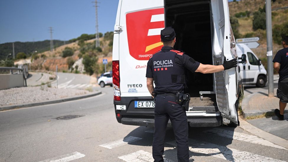 A police officer checks a vehicle at a roadblock set up to find Mr Puigdemont