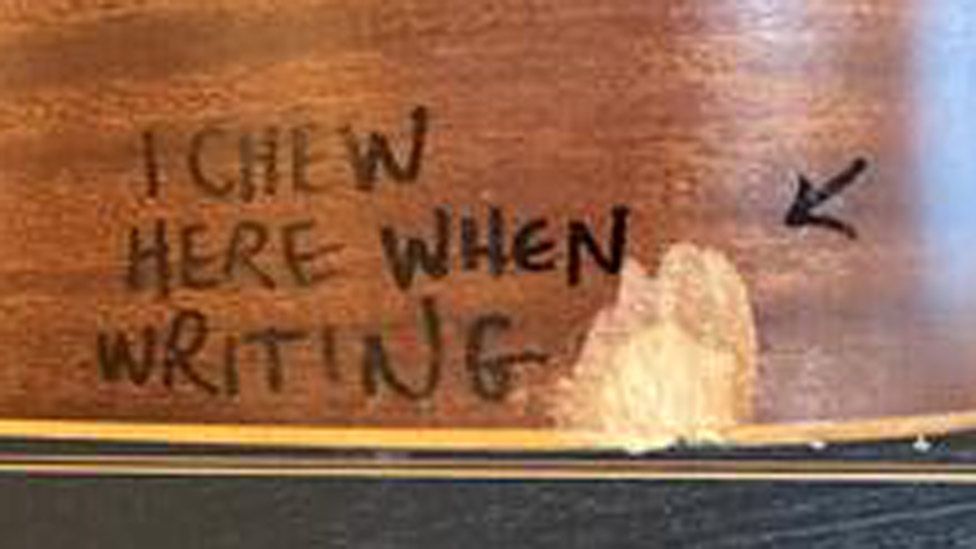 Section of guitar with a chip and an arrow pointing to words saying "I chew here when writing"