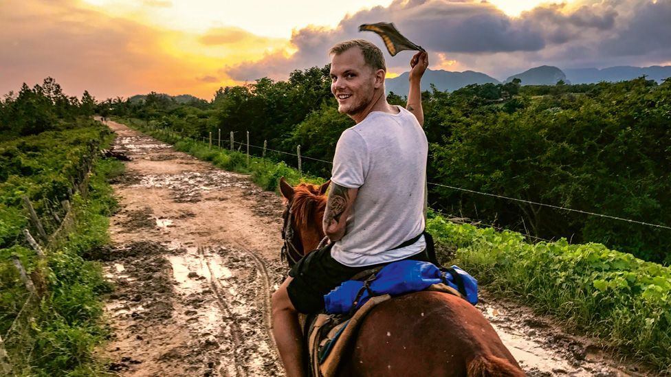 Avicii riding a horse into a sunset
