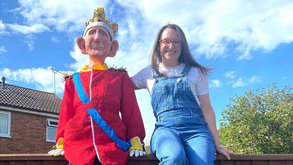 Sharon Kulesa sitting on a fence next to the King Charles model she made.