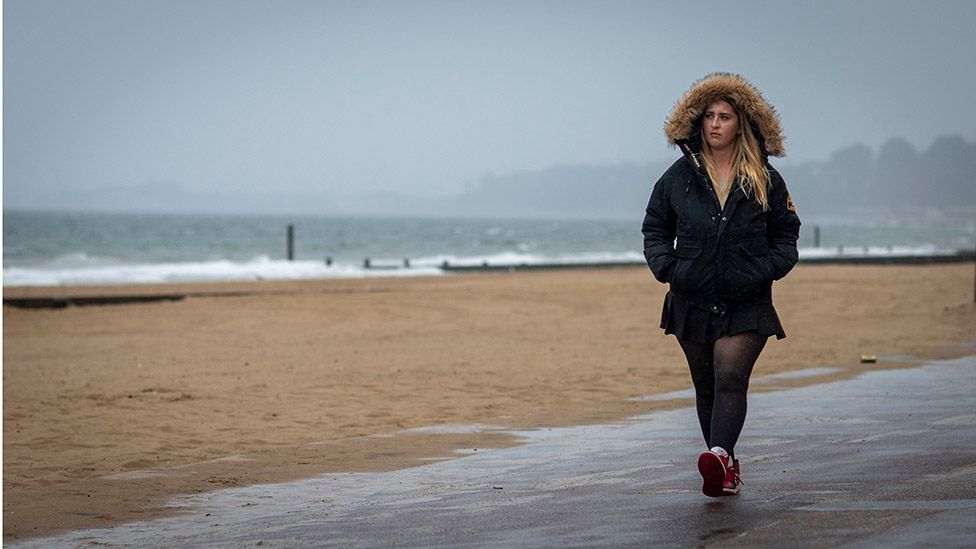 Katy walking by the sea on a grey day