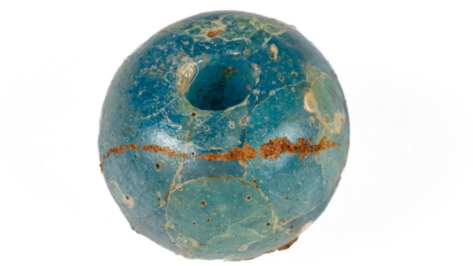 A blue glass bead with a bronze-coloured thread made in the late Bronze Age, found at Must Farm