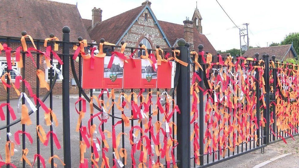 Winterborne Stickland former first school with red, orange and white ribbons tied to its black fence