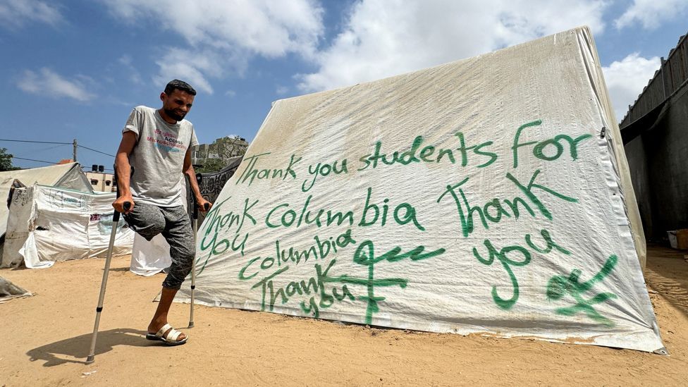 A man uses crutches next to a tent sprayed with a message thanking pro-Palestinian university students who are protesting for their support, amid the ongoing conflict between Israel and Palestinians, in Rafah in the southern Gaza Strip, May 2, 2024