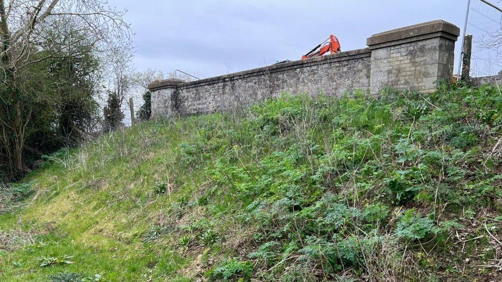 The bridge after it was infilled showing grass and weeds covering its banks