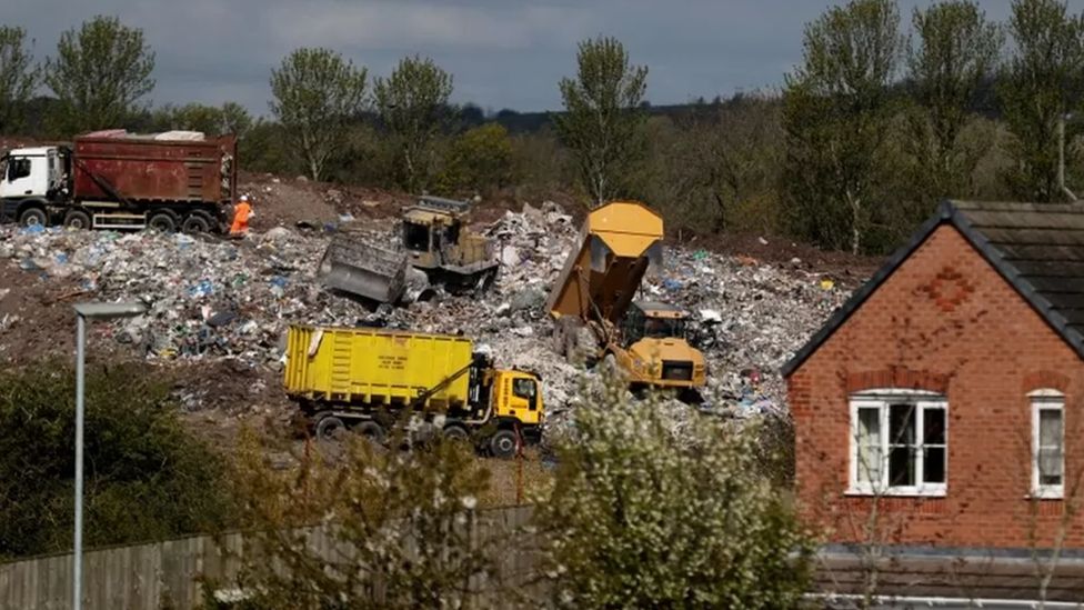 Earth-moving machines are sifting through a mountain of rubbish at Walleys Quarry, with a house up against the fence at the facility