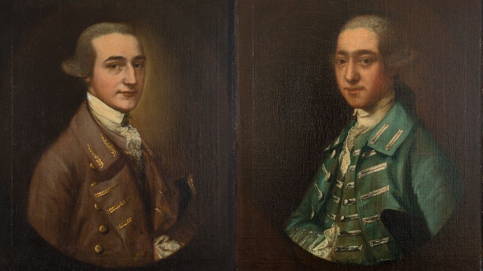 William Tugwell and Thomas Tugwell. William wears a brown regency coat and has a cravat, while Thomas has a green overcoat on. Both have wigs and were painted on a brown background.