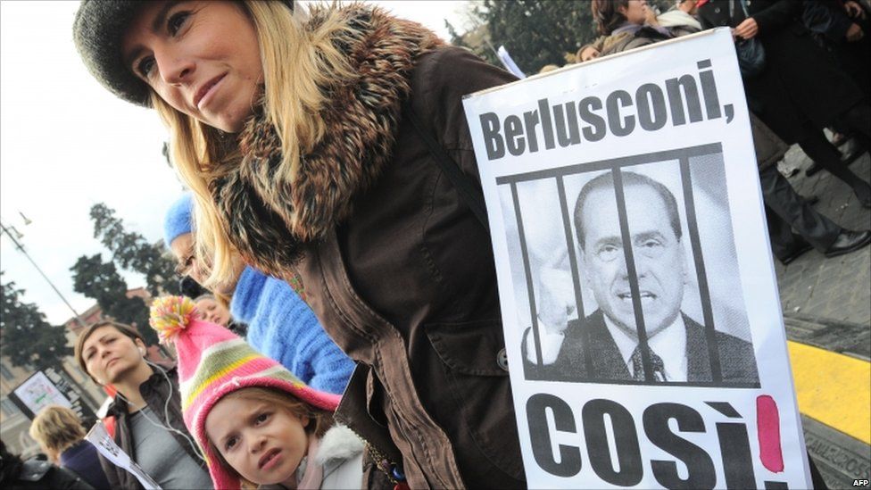 A mother holds a placard reading 'Berlusconi, like that!' at Rome's Piazza del Popolo on 13 February 2011