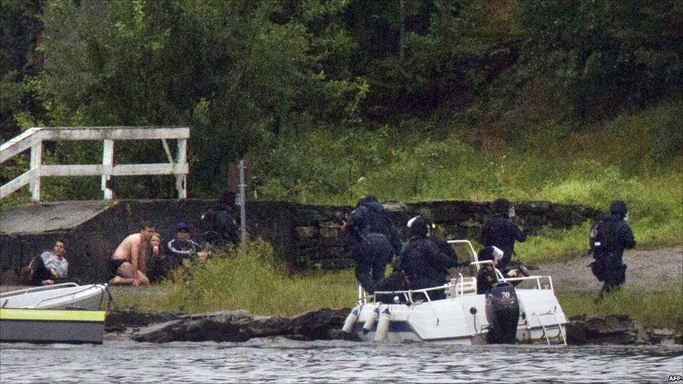 Armed police aim their weapons while people take cover after the shootings on Utoya island, some 40km south-west of Oslo, 22 July 2011