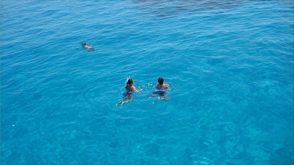 People swimming in the waters of a clear blue sea