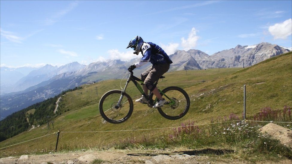 A man jumps over a mound of earth on a mountain bike