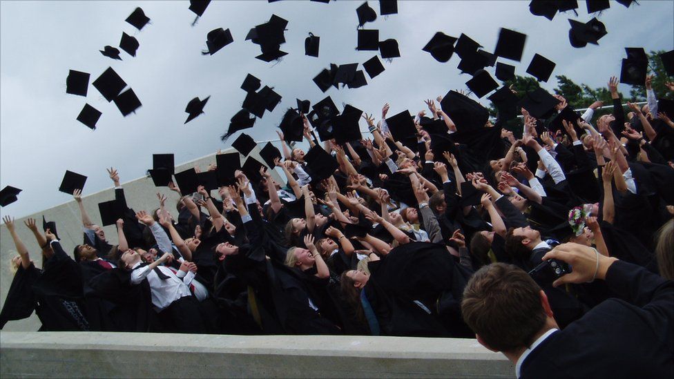 A group of graduating students throw their mortar boards in the air